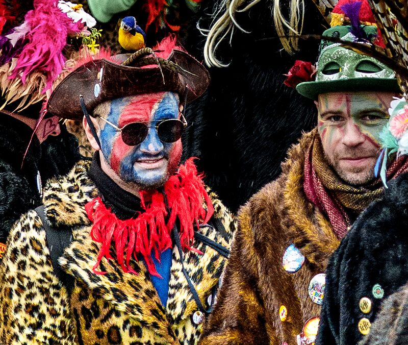 Détail sur masque carnavalesque orné de plumes multicolores et maquillage festif à Dunkerque.