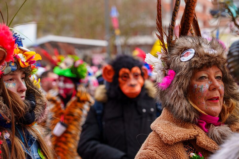 Gros plan sur masques carnavalesques ornés de plumes multicolores et maquillage extravagant.