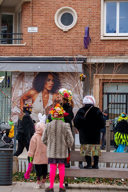 Détail sur masque carnavalesque orné de plumes multicolores et maquillage festif à Dunkerque.