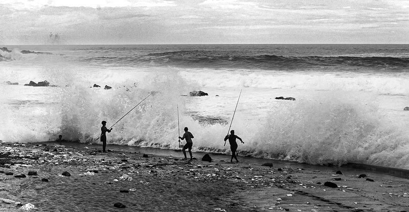 Pêcheurs surpris par une vague sur la plage de Grand Anse, Réunion.