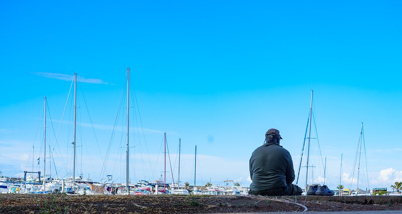 Badeau assis sur un muret face au port de pêche de Terre-Sainte, Réunion 2025.