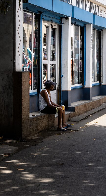 Vieil homme assis devant une boutique à Grand Baie, Ile Maurice 2026.
