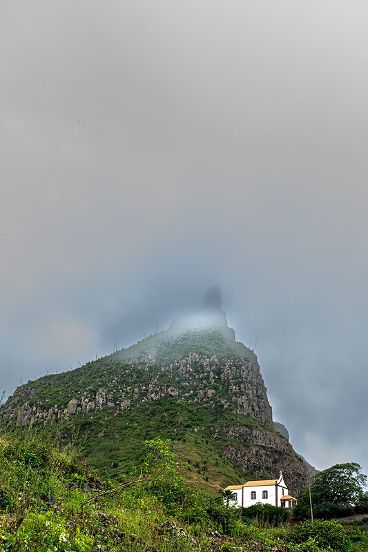 Petite chapelle blanche au pied d'un pic montagneux dont le sommet est dans le brouillard, Cap-Vert, 2016.